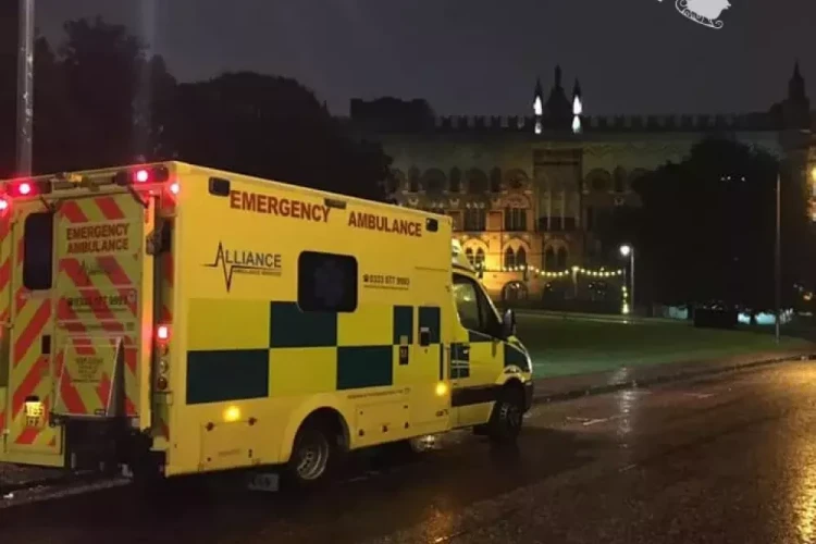 An Alliance Ambulance is parked on a quiet, rainy night in front of an illuminated building. Above, a silhouette of Santa’s sleigh and reindeer adds a festive touch, highlighting the holiday spirit.
